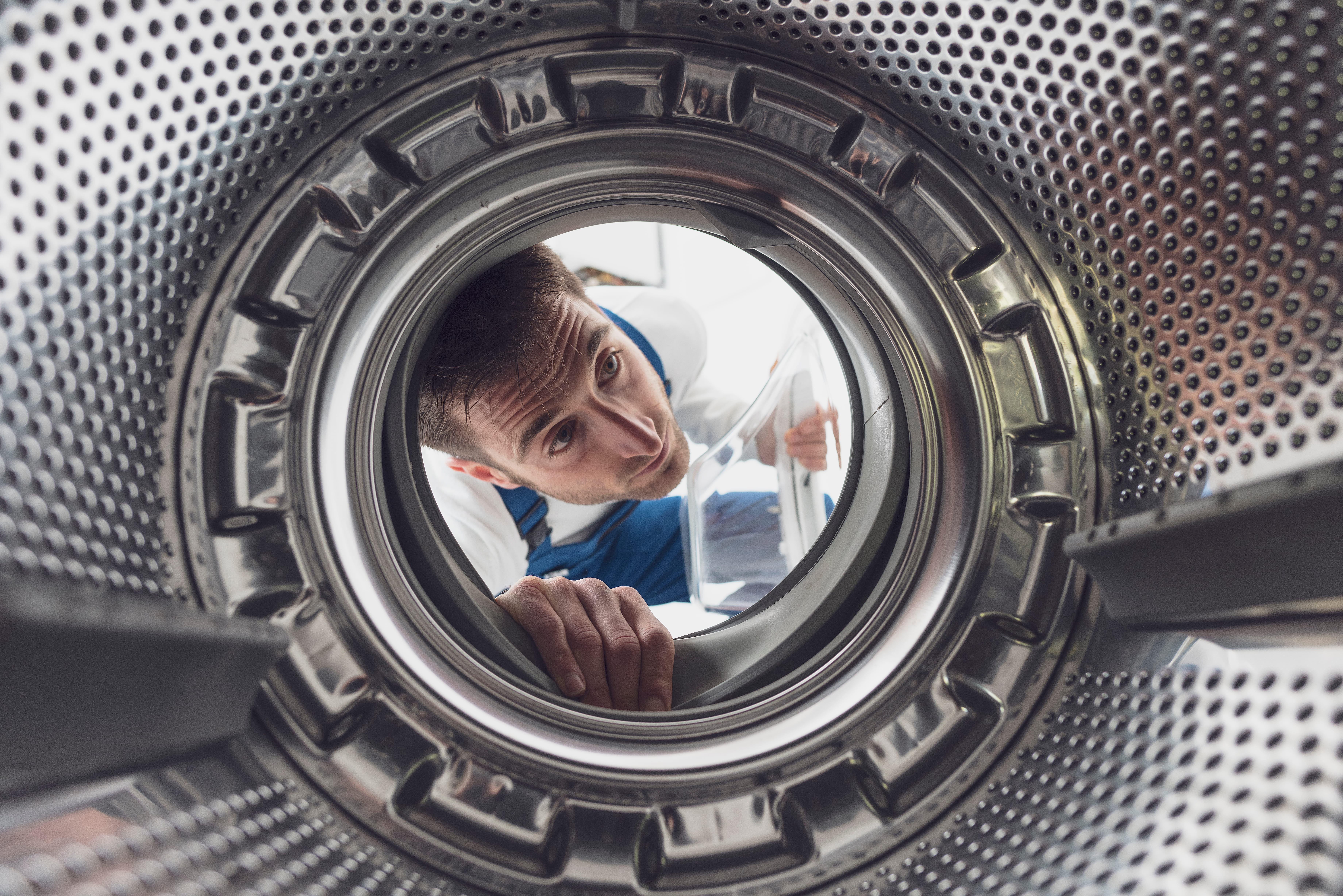 Appliance technician diagnosing a washing machine drum fault on site