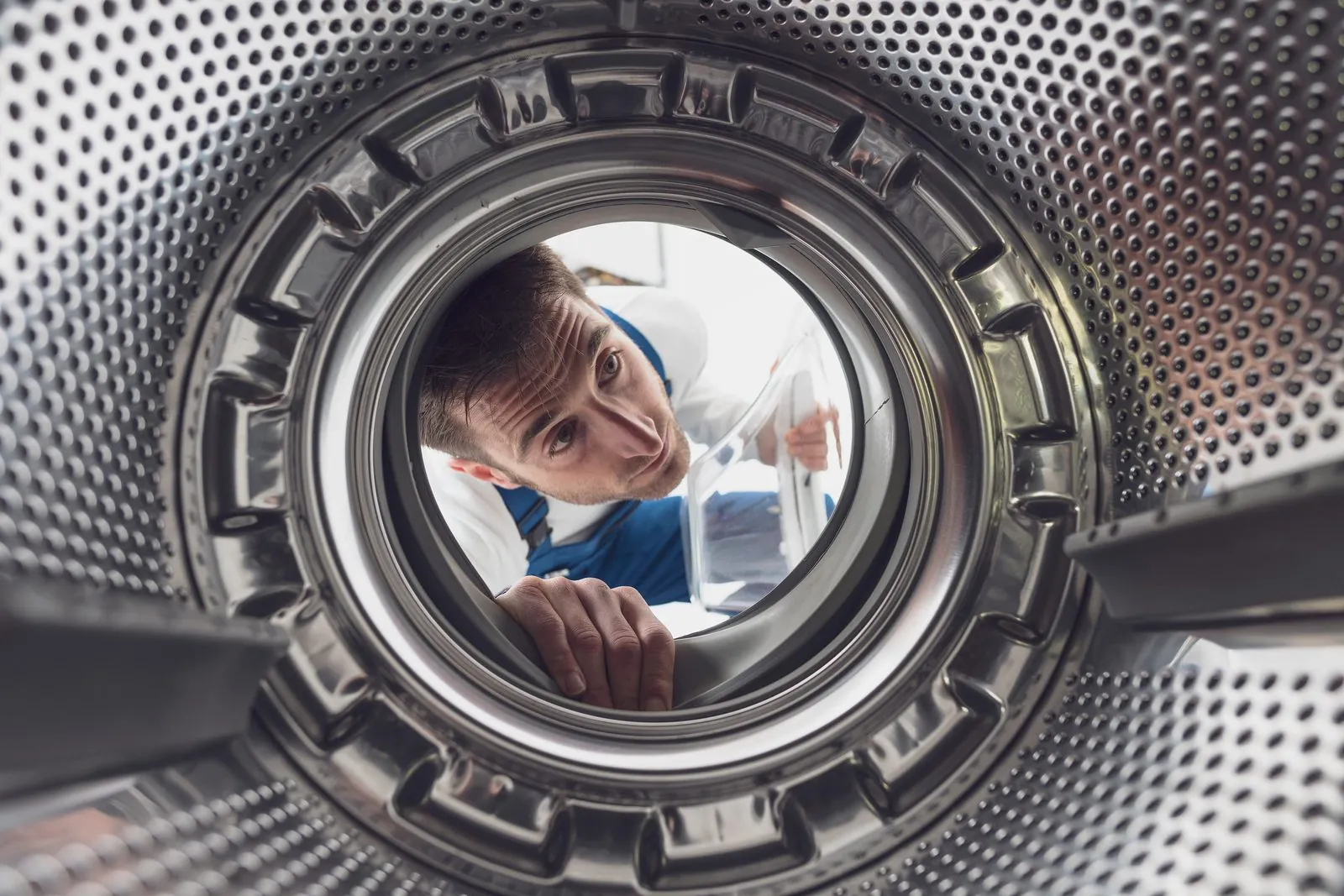 Technician inspecting a washing machine drum Technician inspecting a washing machine drum