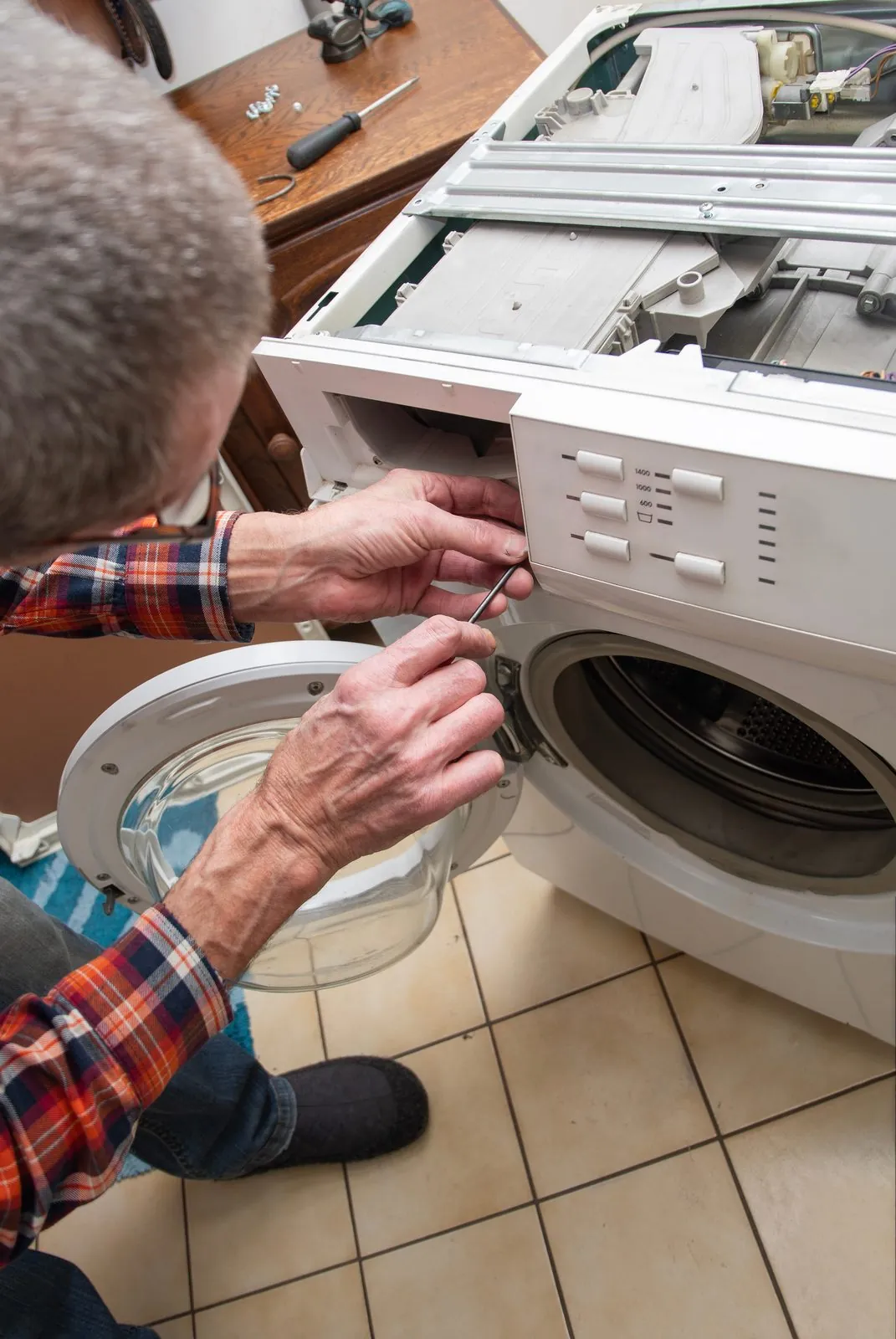 Technician carrying out a washing machine repair on site
